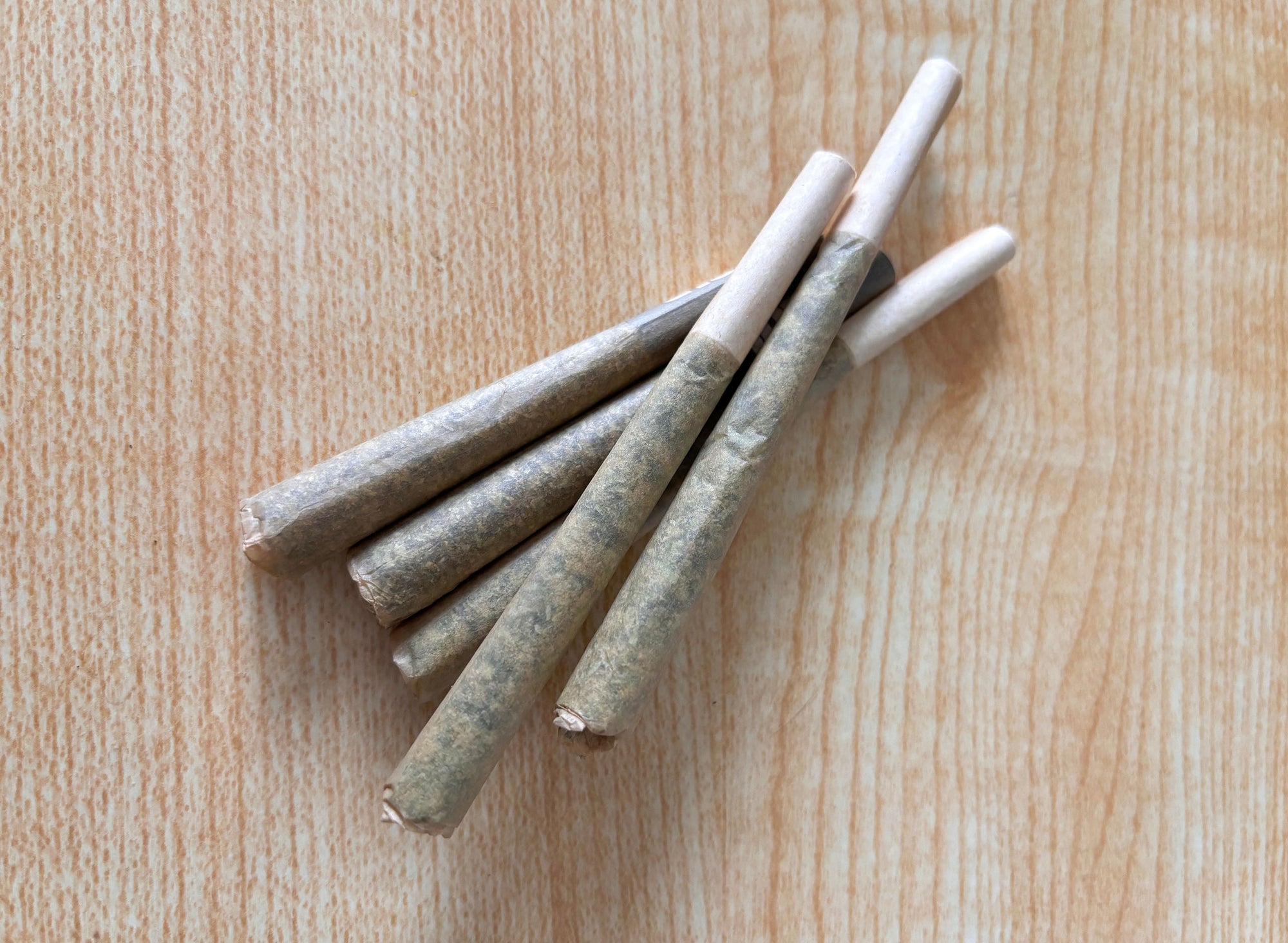 Nine cylindrical containers of varying heights wrapped in brown paper, some with black tops, one with a white spray nozzle