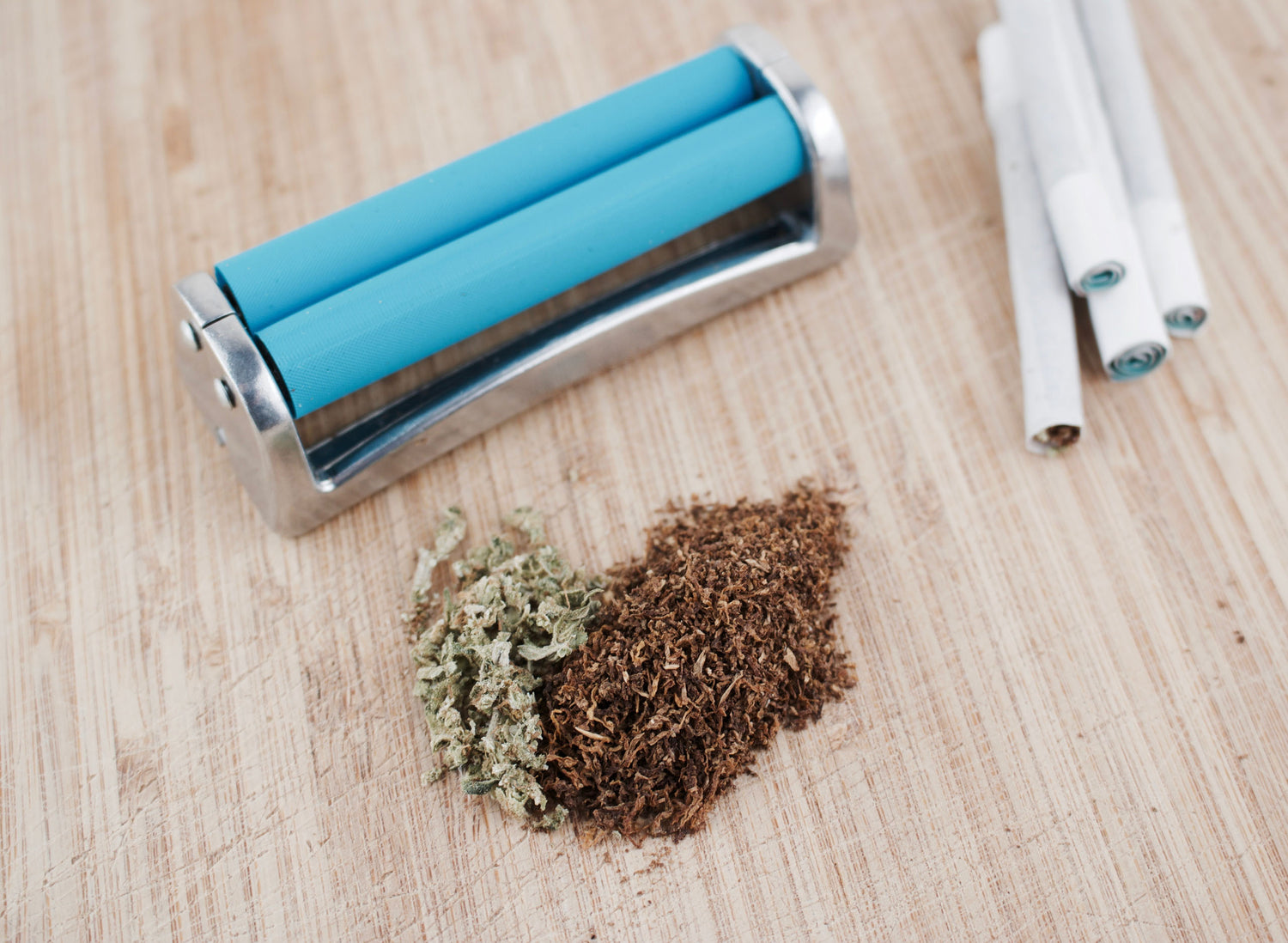 Teal machine with white paper roll, two brown rolls, and white powder on pink surface
