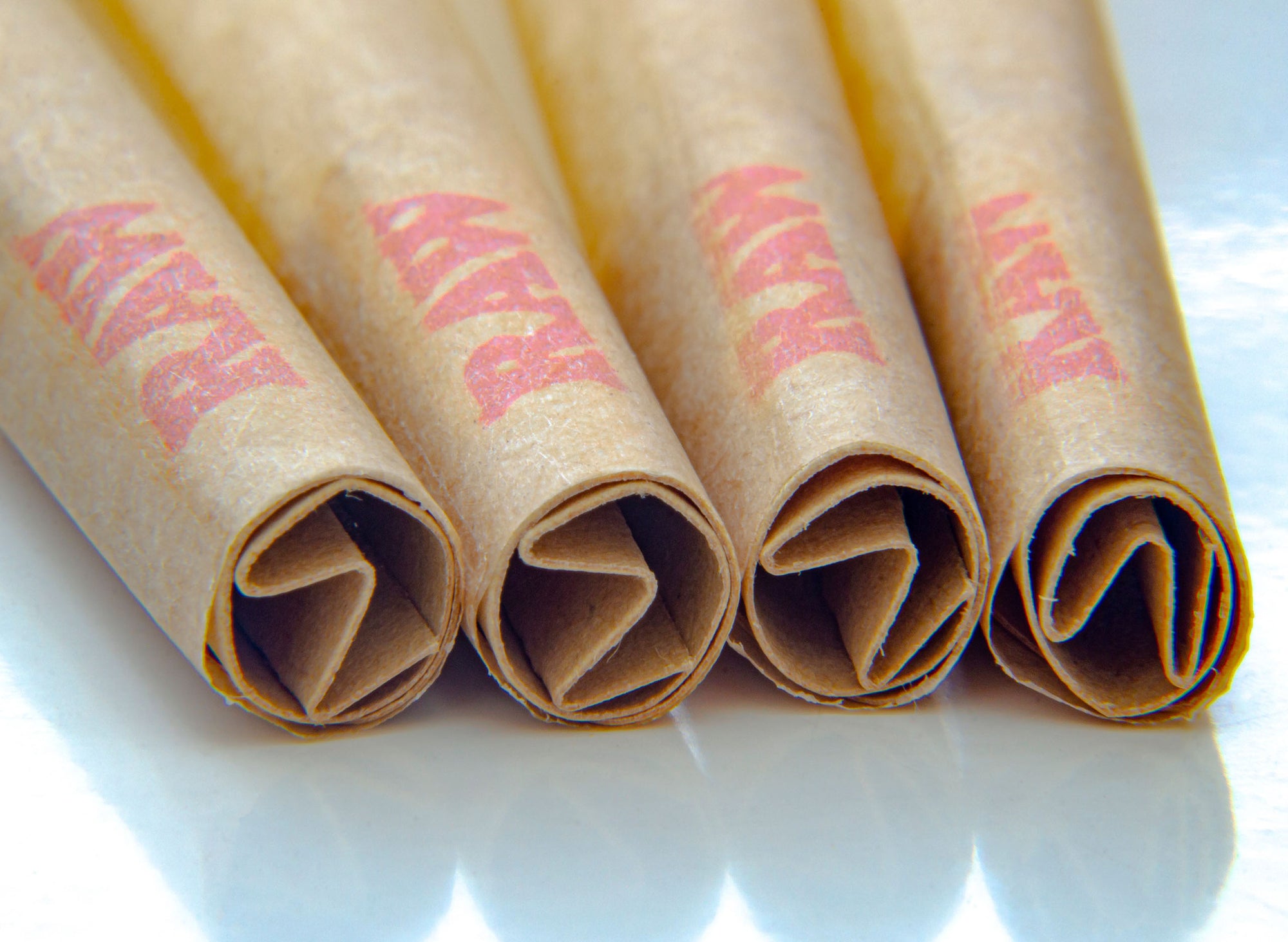 Five cigars with burning ends, smoke rising, next to a pile of white crystals on a wooden surface